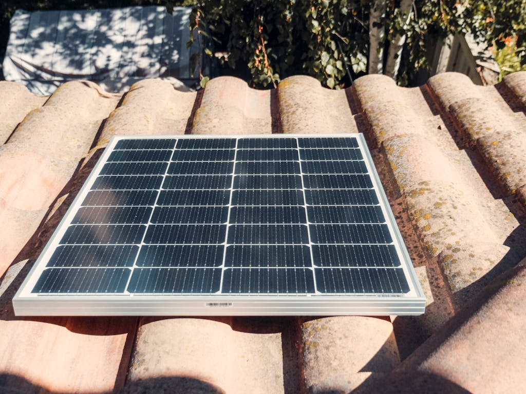 A single solar panel on a rustic tiled roof gleaming in sunlight. Eco-friendly energy.
